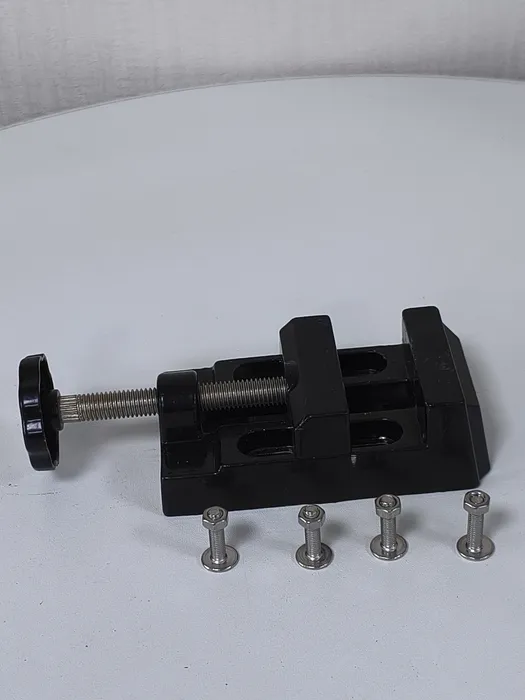 V1 Mini Bench Vise in black with its four stainless mounting bolts laid alongside