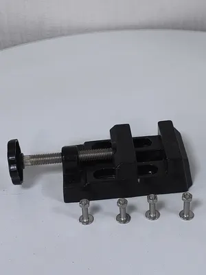 V1 Mini Bench Vise in black with its four stainless mounting bolts laid alongside