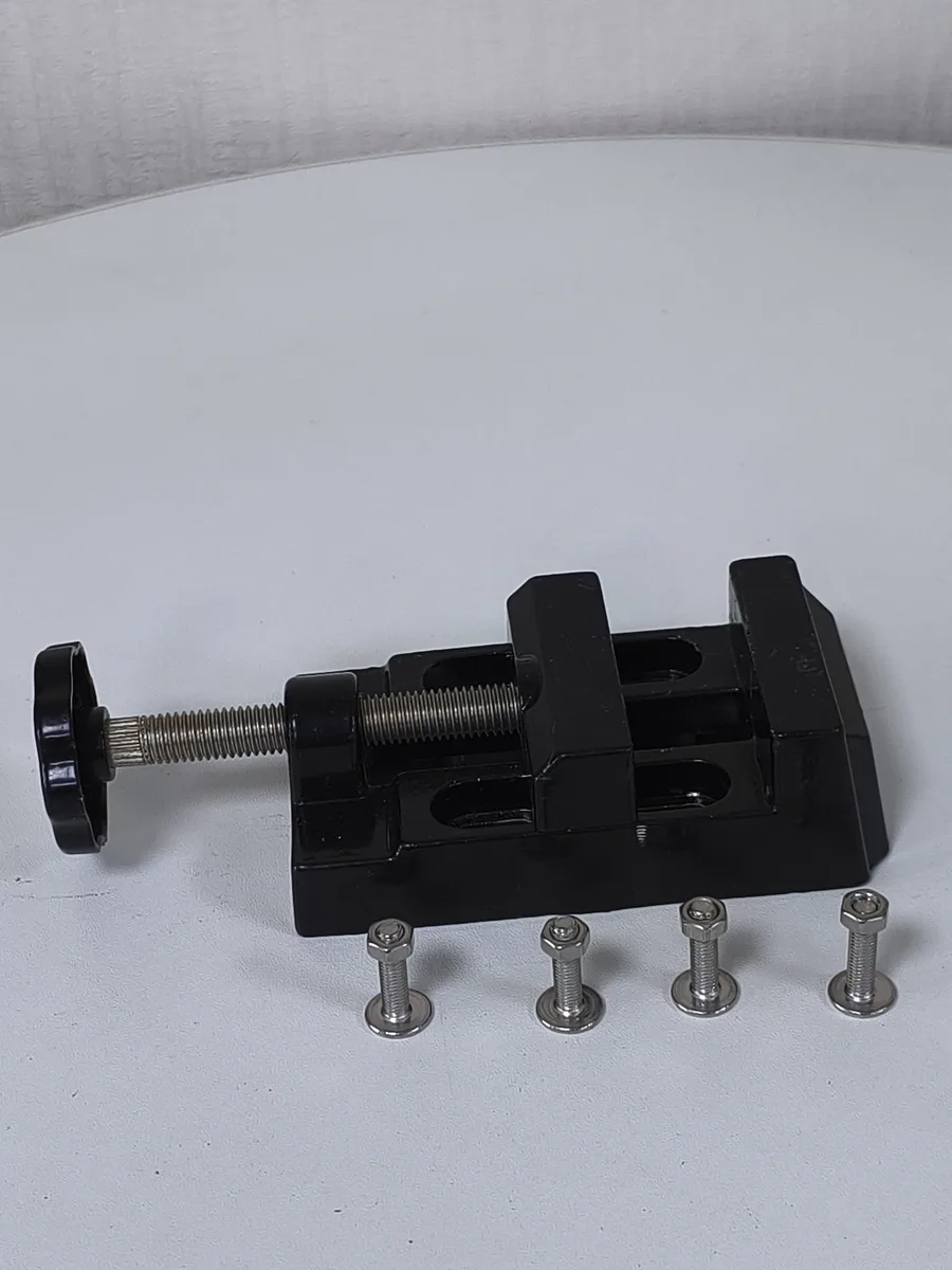 V1 Mini Bench Vise in black with its four stainless mounting bolts laid alongside